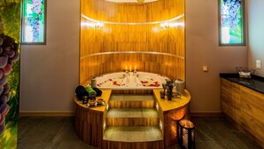 A spa room with a large bathtub, wooden paneling, and a chandelier.