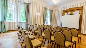 Un salón de conferencias con papel tapiz a rayas, suelo de madera y una pizarra.