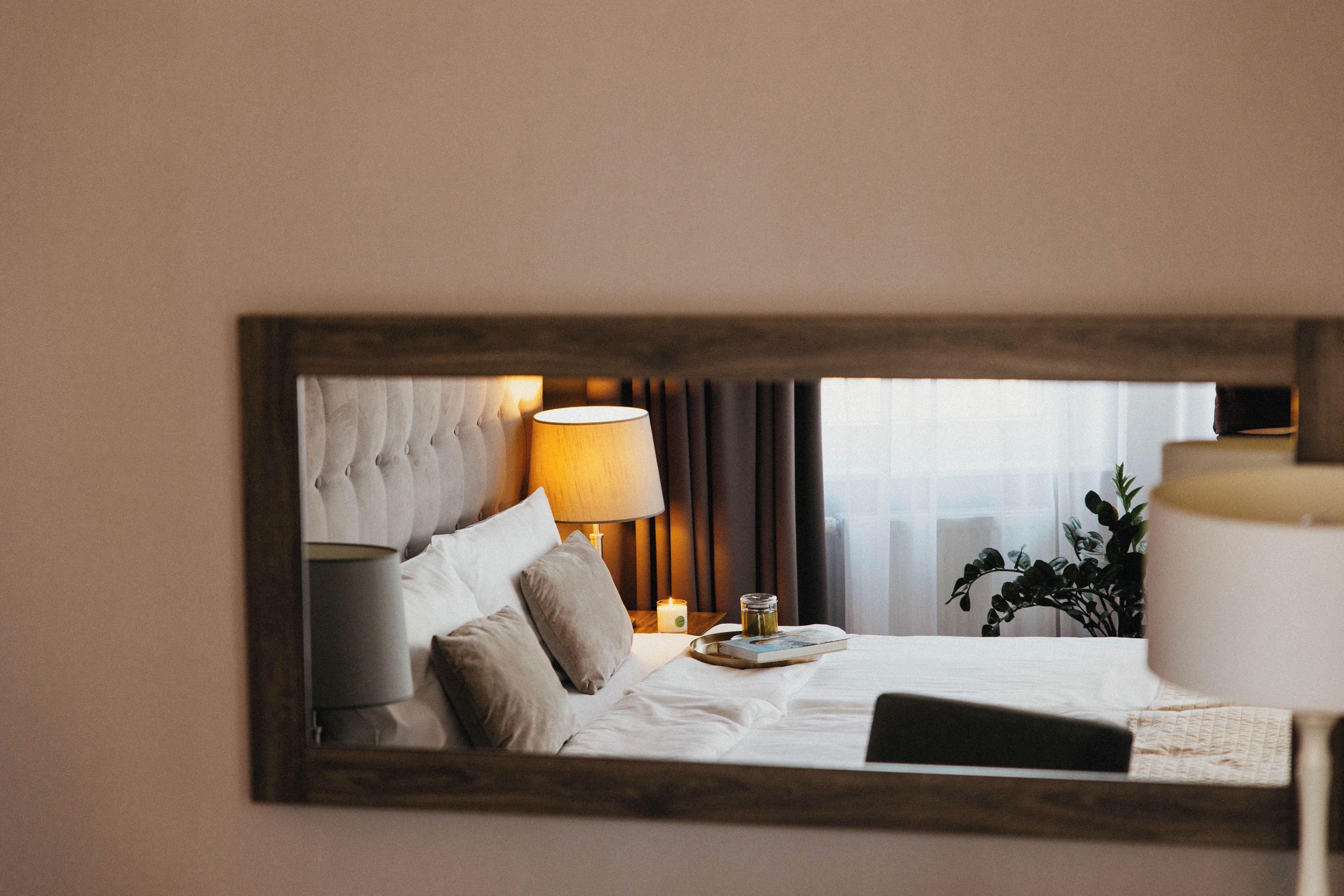A hotel room with a bed, a nightstand, a lamp, and a window with curtains.