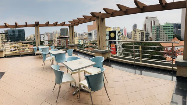 A rooftop terrace with outdoor seating, a city view, and a pergola structure. - Golden Park Hotel (Luanda)