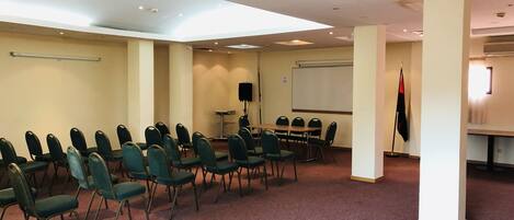 A conference room with rows of green chairs, a whiteboard, a projector, and a flag.