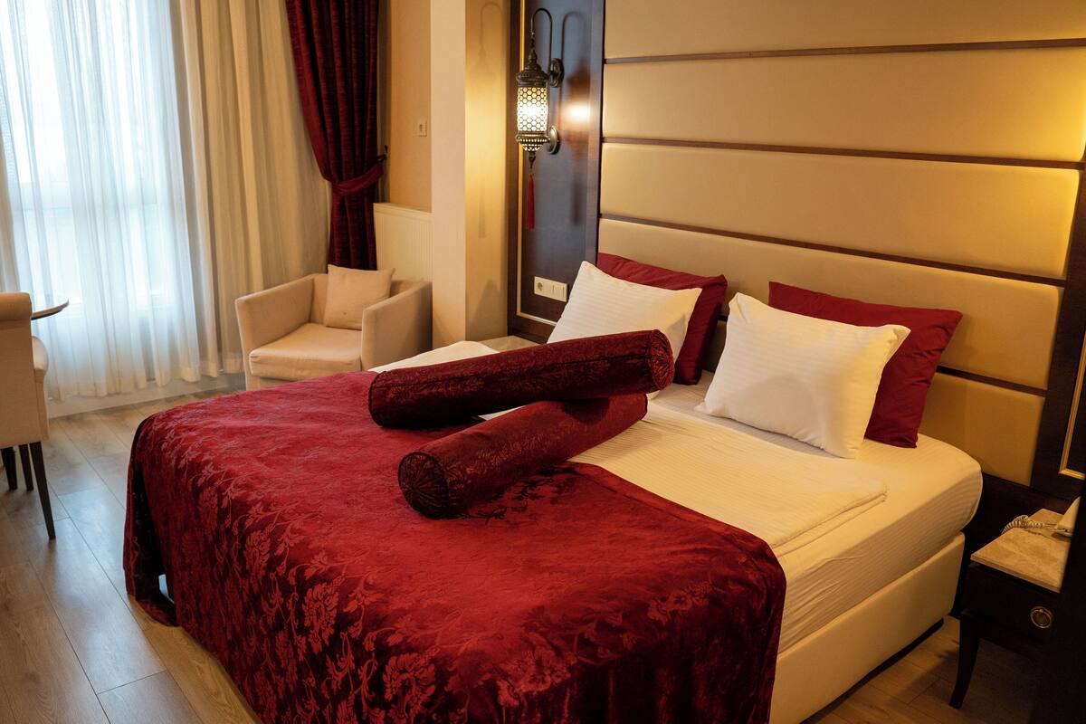 Quarto de hotel com uma cama grande, uma cadeira, uma mesa de cabeceira e um abajur.