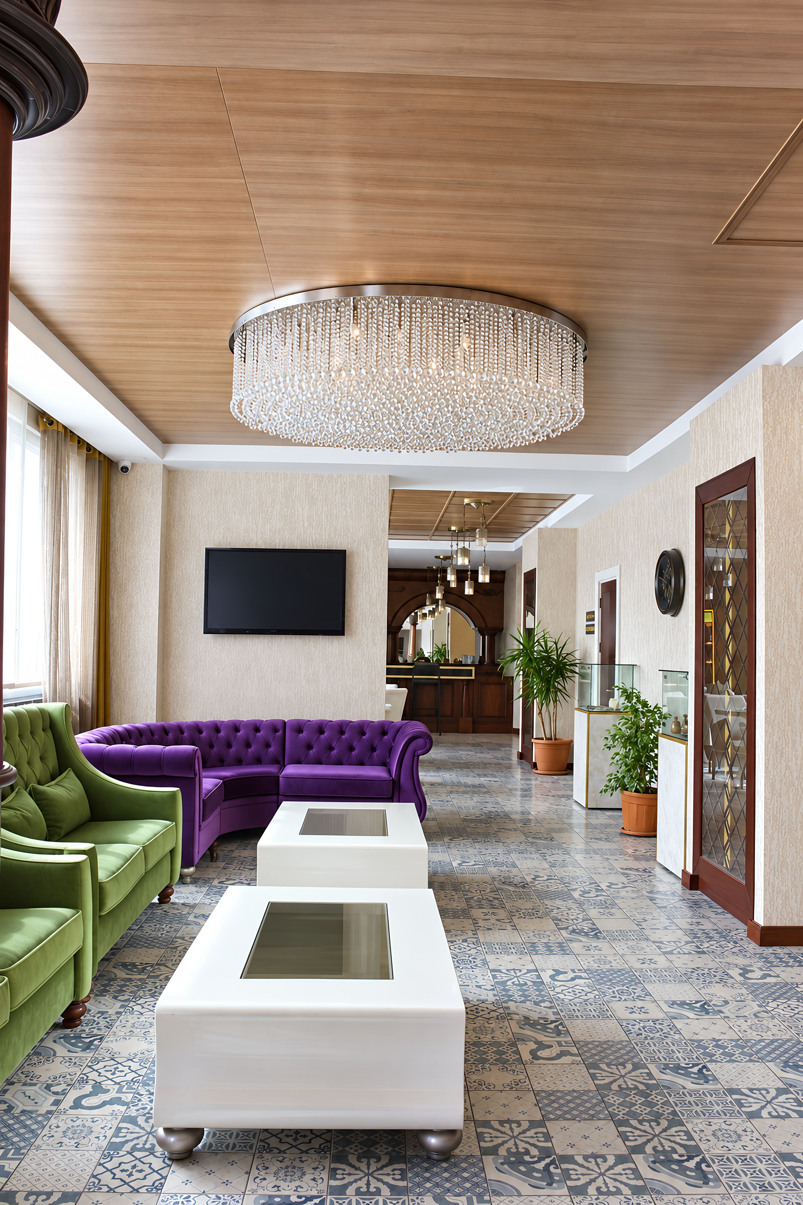 Un hall d’hôtel moderne avec un canapé d’angle, un téléviseur à écran plat, un lustre et des carreaux de sol à motifs.