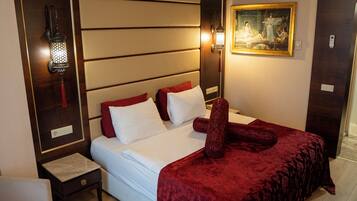 A hotel room with a large bed, a nightstand, a wall-mounted lamp, and a painting.