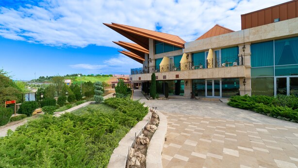 A modern building with a courtyard, a large glass facade, and a distinctive roof design.