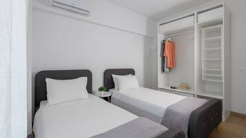 A hotel room with two beds, a wardrobe, and a small table with a plant.