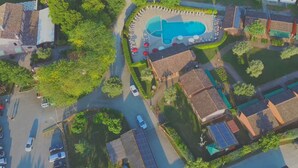 Vista aérea de una zona residencial con piscina, paneles solares y aparcamiento.
