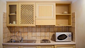 Una cocina con armarios de madera, microondas, lavaplatos y salpicadero de azulejos.