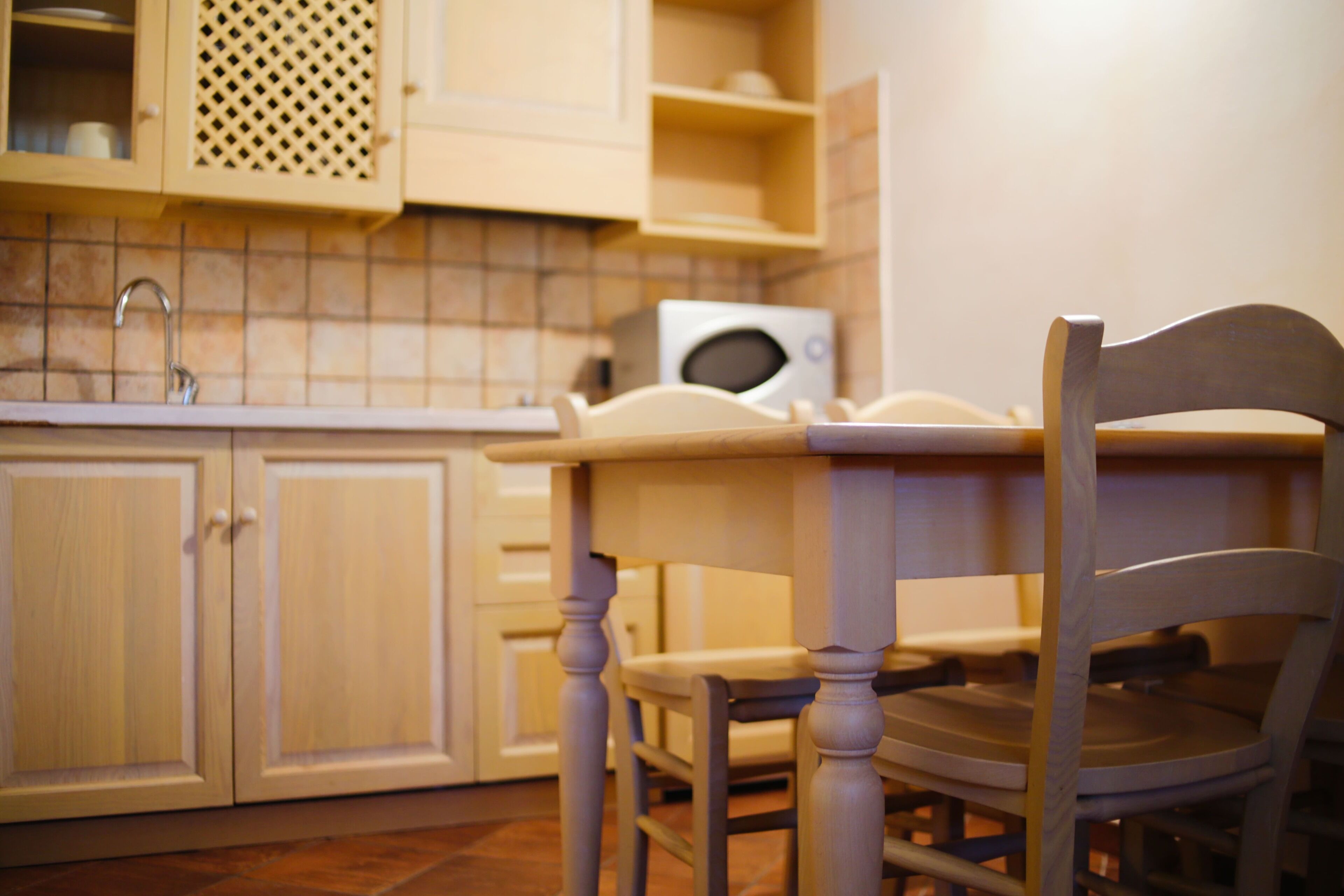 Una cocina con armarios de madera, un microondas y una silla.