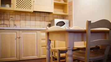 Una cocina con armarios de madera, un microondas y una silla.