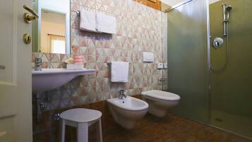 Une salle de bain équipée d’un lavabo, de deux bidet, d’un miroir et d’une douche.