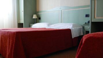 Ein Hotelzimmer mit einem Einzelbett, einem Nachttisch, einer Lampe und einem kleinen Tisch mit Telefon.