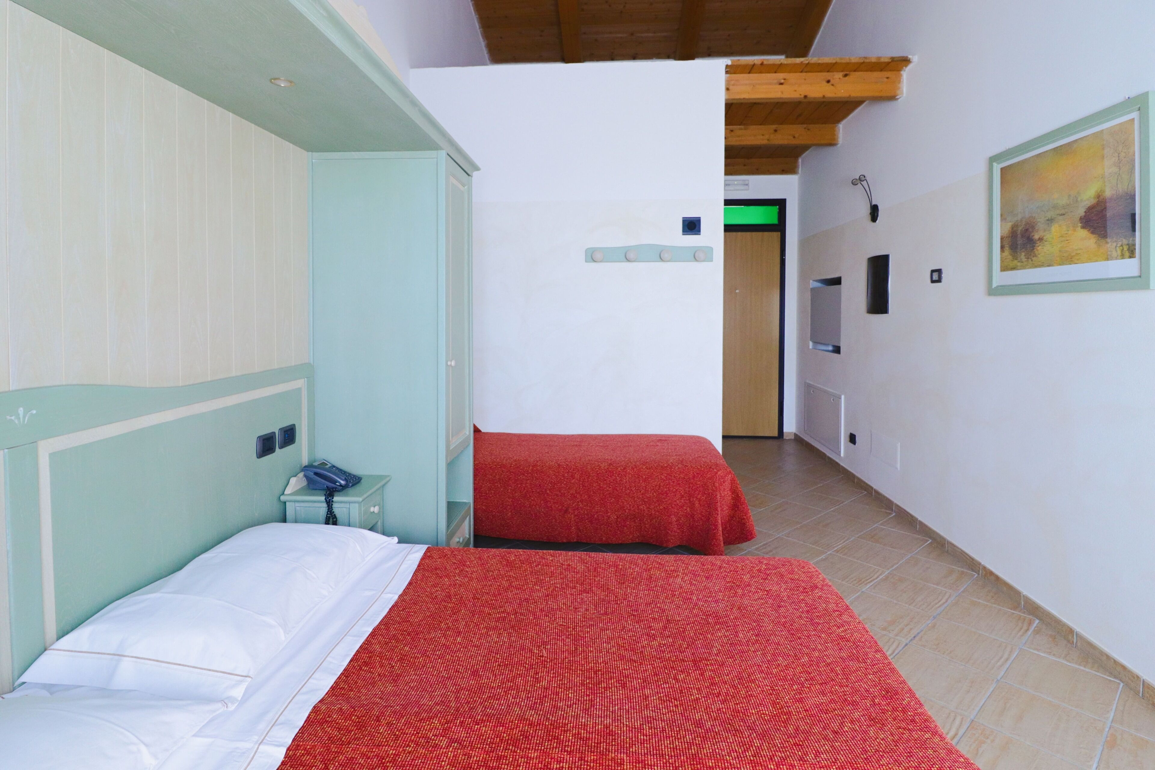 Una habitación con dos camas, un teléfono y un cuadro en la pared.