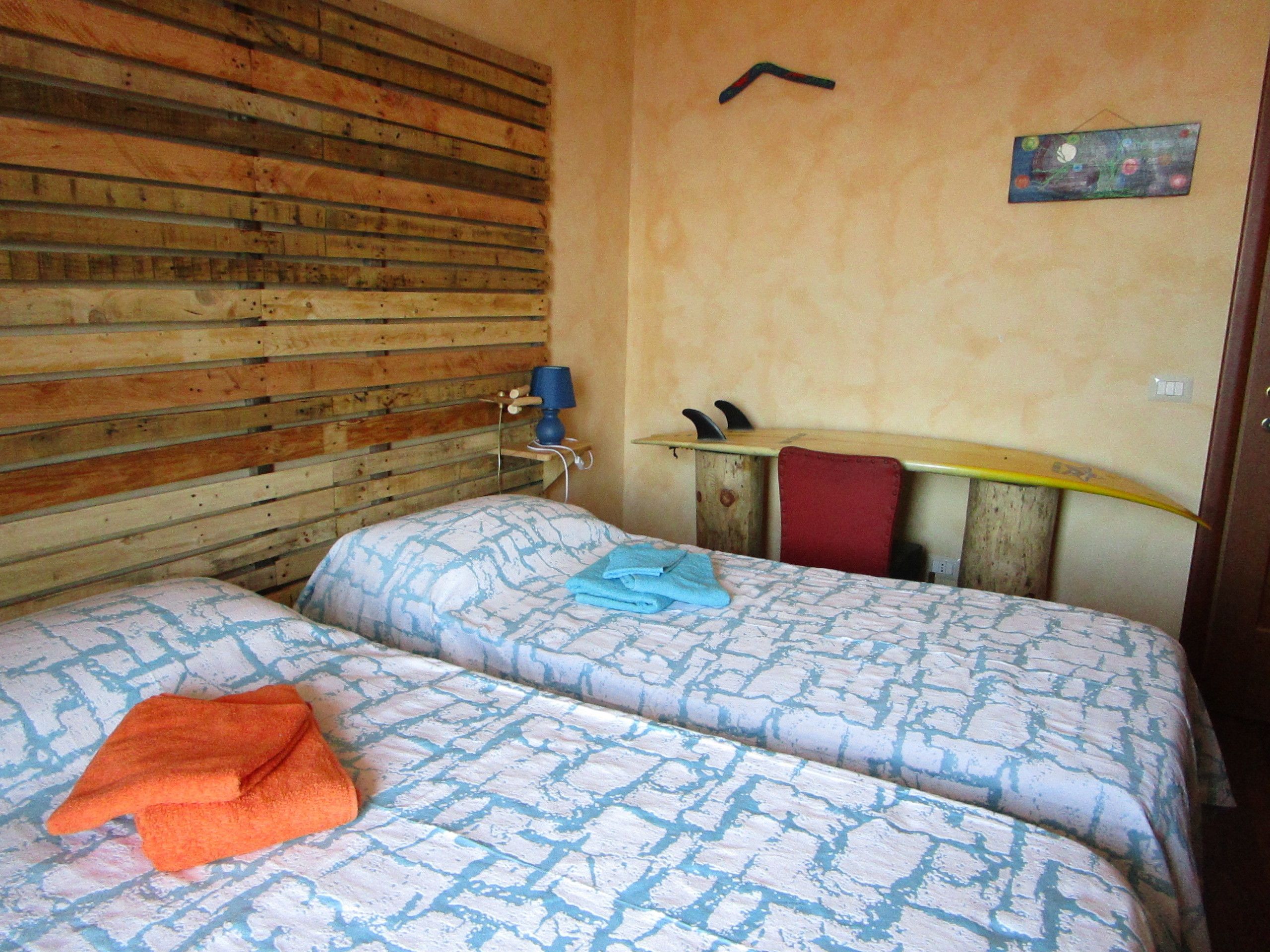 Una habitación con dos camas, cabecera de madera, una tabla de surf y un soporte para tabla de surf.