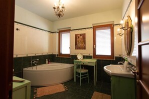 A bathroom with a bathtub, a sink, a chair, and a mirror.