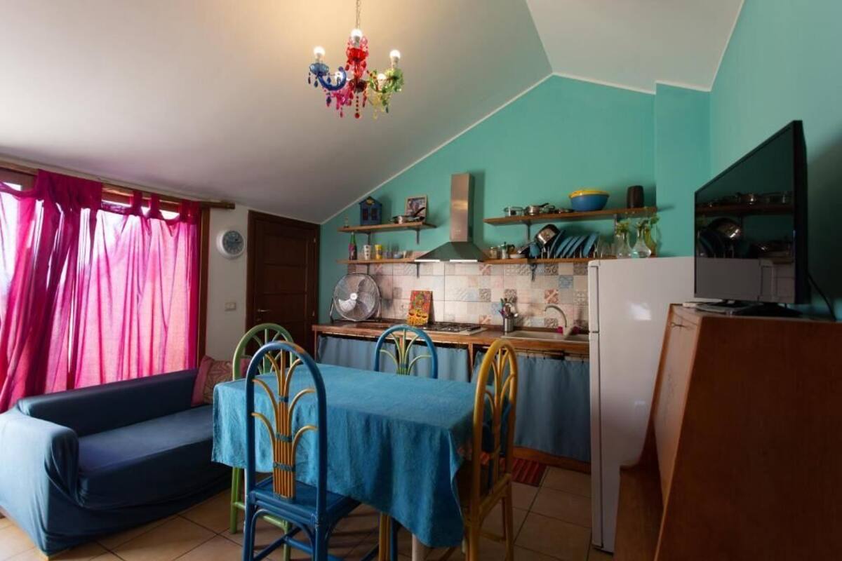 Una cocina compacta con comedor, un sofá y una lámpara de techo colorida.