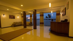 Een moderne hotel lobby met een receptiebalie, een bank en een grote spiegel.