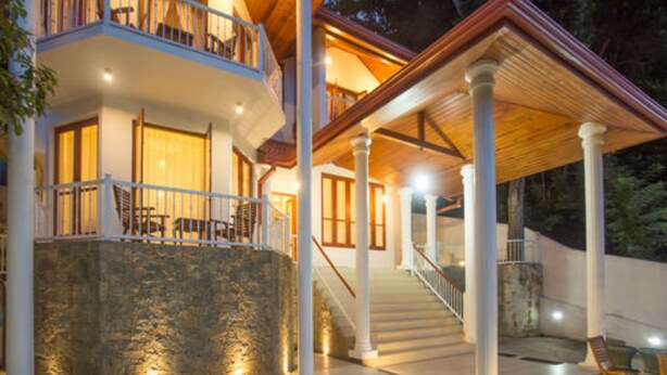 A two-story house with a swimming pool, stone wall, and a covered patio area. - Orchid Villa Kandy (Kandy)
