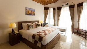 A hotel room with a wooden ceiling, a bed with a checkered bedspread, a bedside table with a lamp, a nightstand with a phone, and a window with curtains. - Orchid Villa Kandy (Kandy)