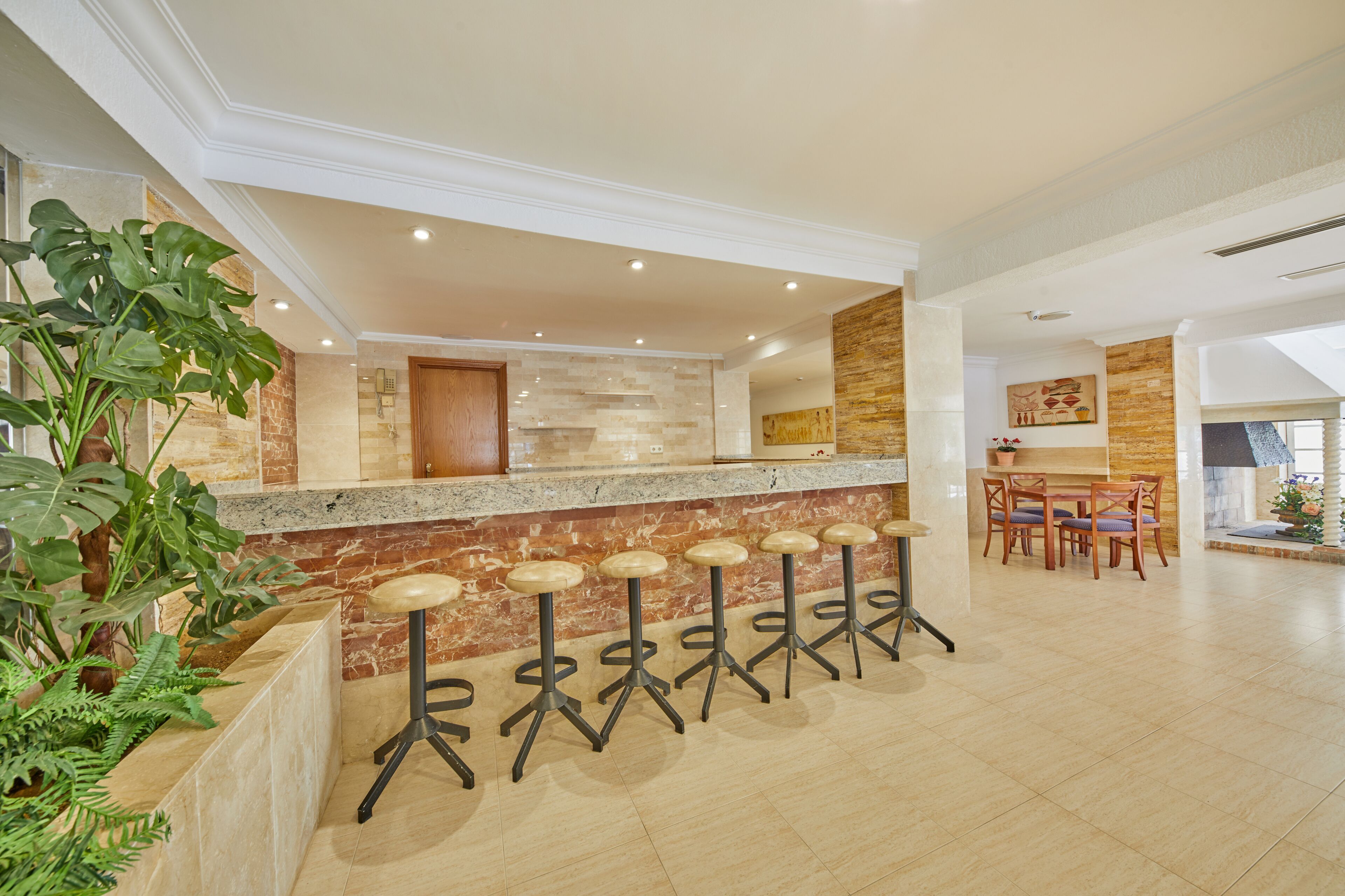 A modern kitchen with a granite countertop, a wooden door, and a dining area with a table and chairs.