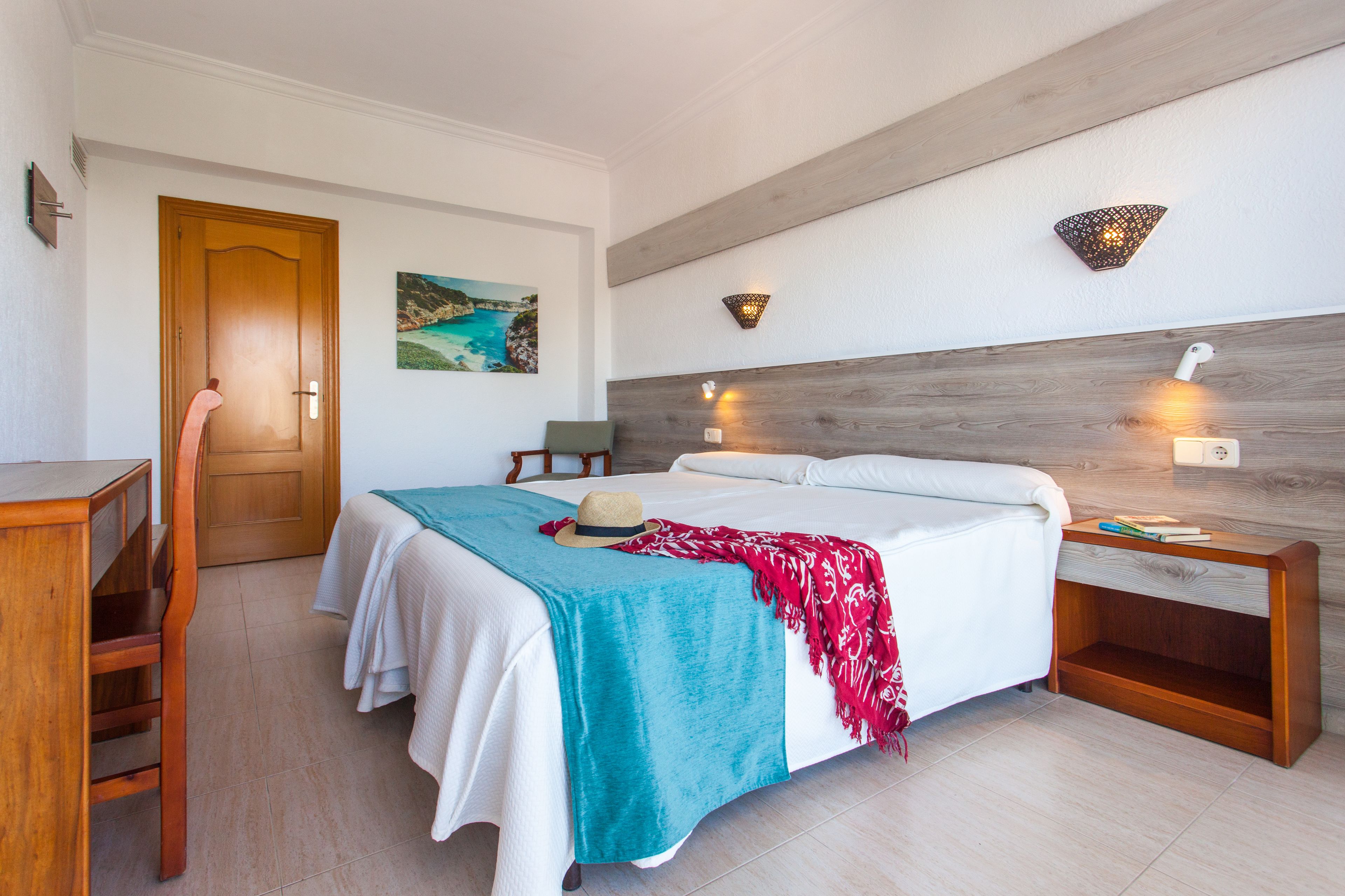 Una habitación de hotel con cama, mesita de noche y escritorio.