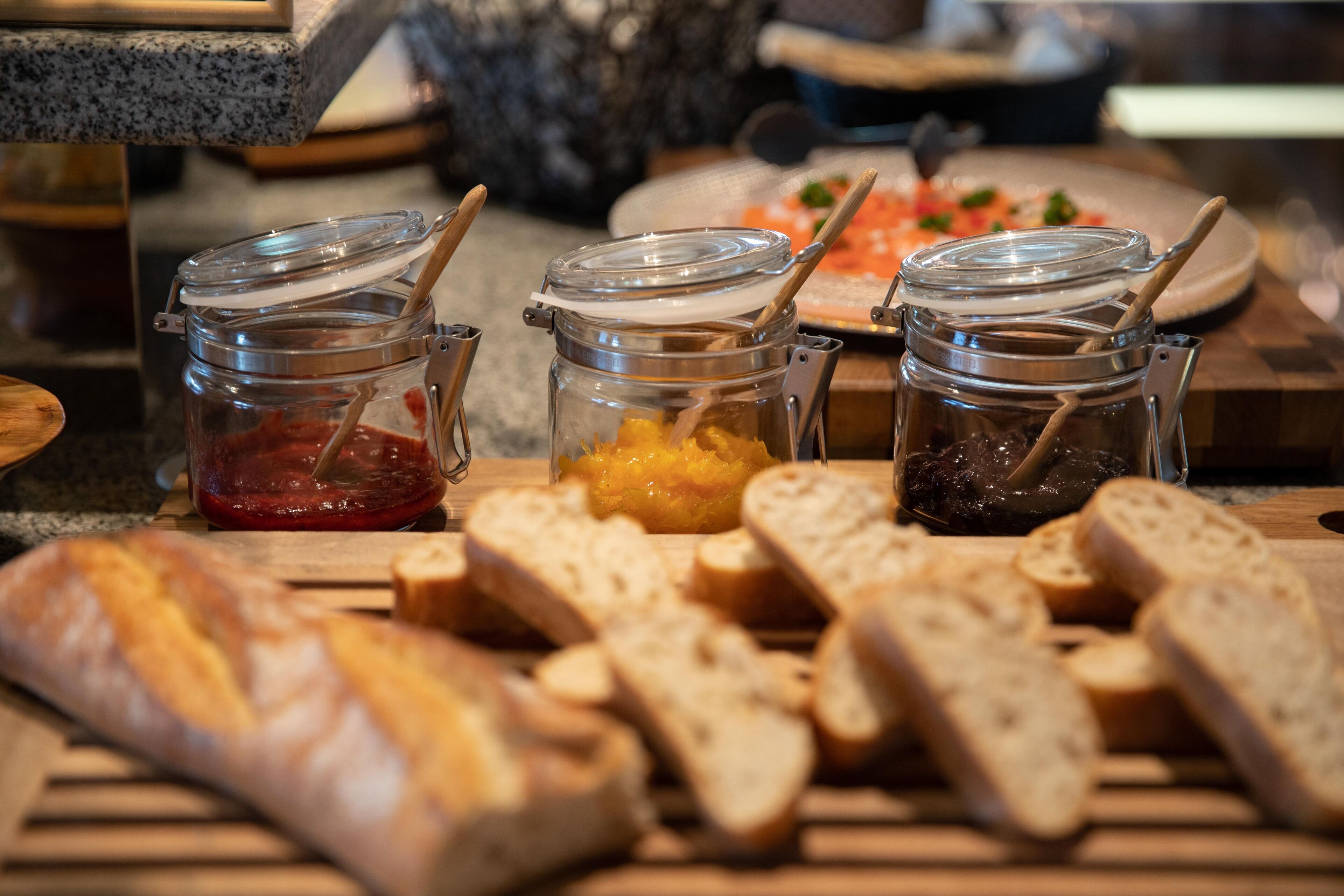 A buffet table with various food items including bread, jams, and spreads.