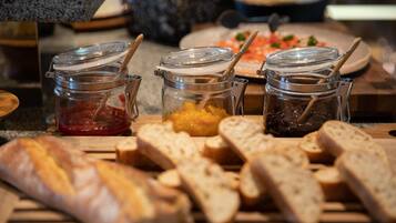 A buffet table with various food items including bread, jams, and spreads.