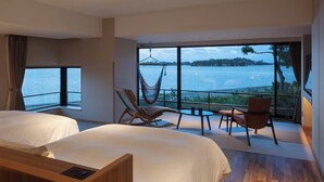 A hotel room with two beds, a hammock, a table, and a view of a lake.