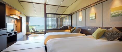 Une chambre d’hôtel avec deux lits, un bureau avec une télévision et une vue sur la mer.