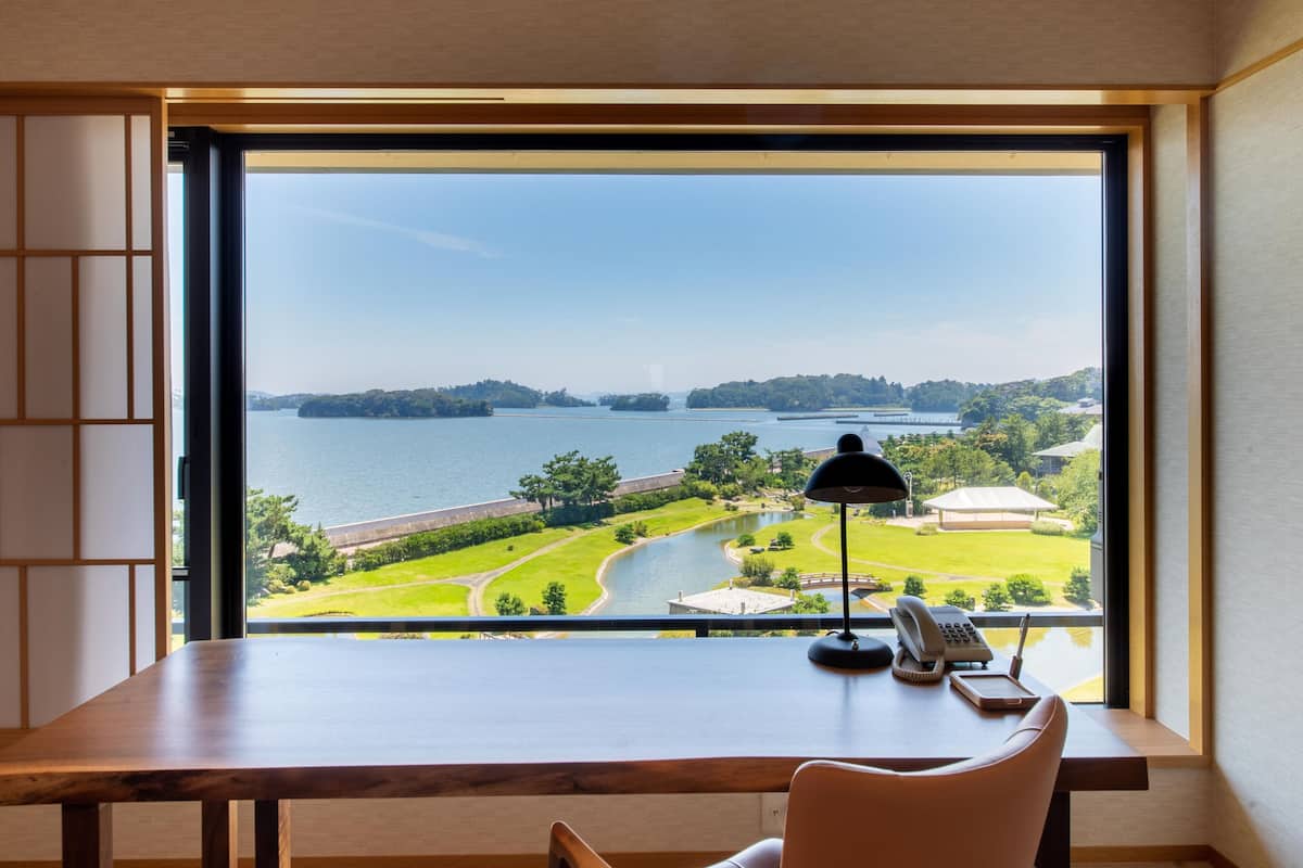 A desk with a view of a lake and park.