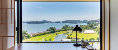 A desk with a view of a lake and park.