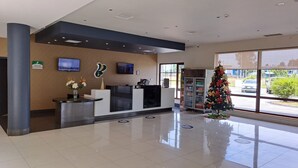 A reception area with a modern design, including a reception desk, a television, and a Christmas tree. - Hotel Diego de Almagro Osorno (Osorno)