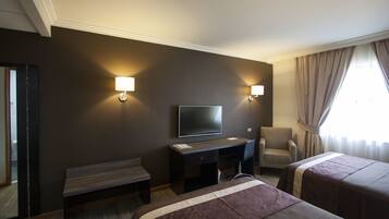 Una habitación de hotel con cama, escritorio, silla y televisor.