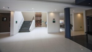 A spacious lobby with a staircase, a reception desk, and a large pillar. - Hotel Diego de Almagro Osorno (Osorno)