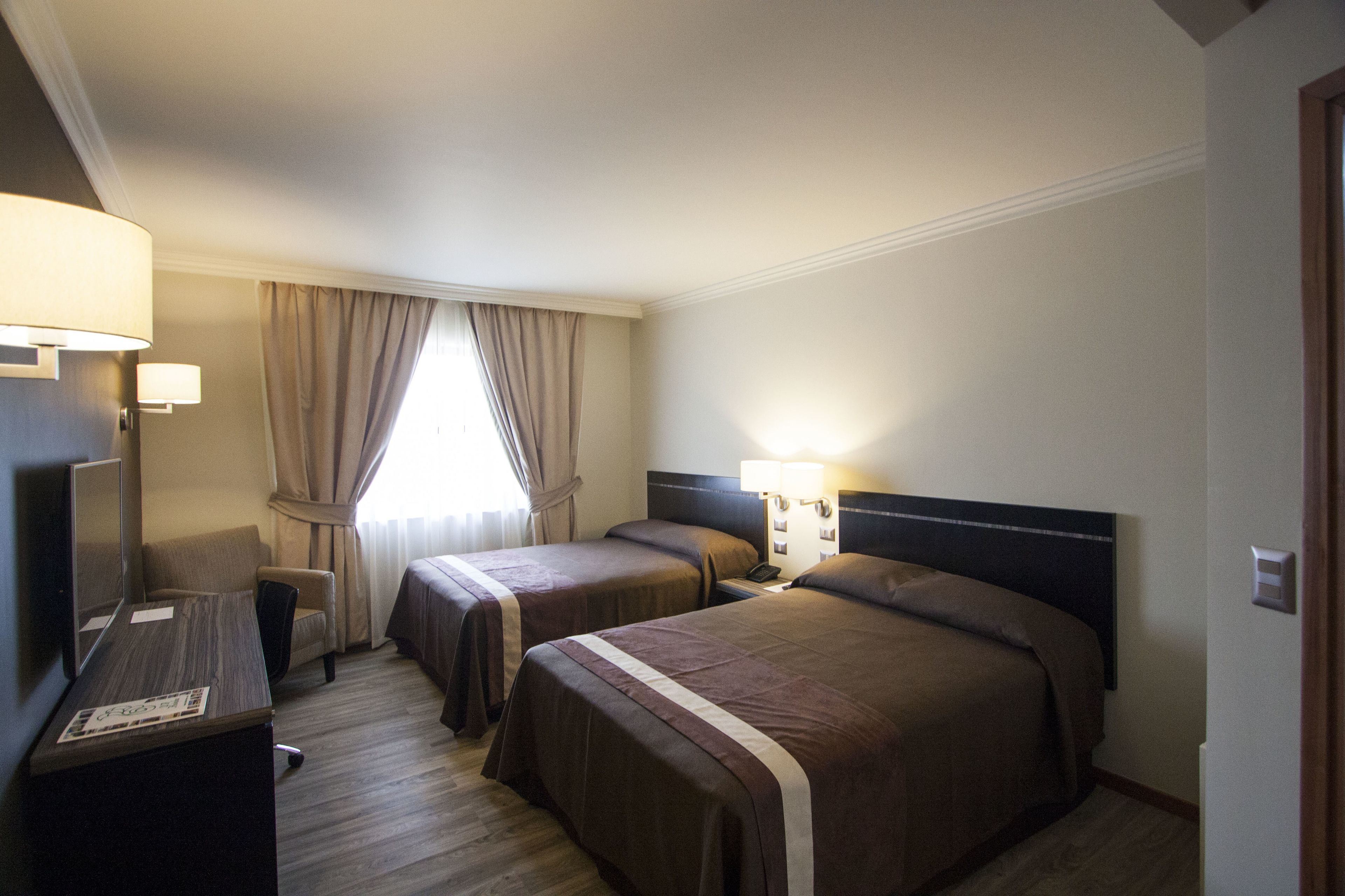 Une chambre d’hôtel avec deux lits, un bureau et une chaise.