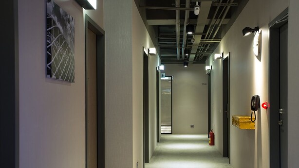 A hallway with doors on both sides, a fire extinguisher, and a phone on the right wall. - Let’s Hostel (Kaohsiung)