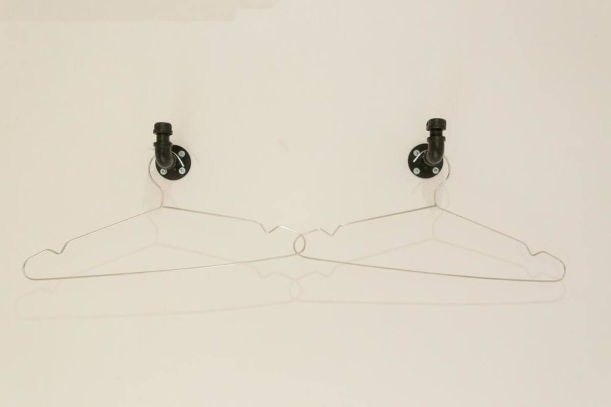 Deux cintres transparents en plastique, fixés au mur.