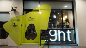 A brightly lit hotel entrance with a large illuminated 'ght' sign, a neon cat silhouette, and a signboard with contact information. - Let’s Hostel (Kaohsiung)