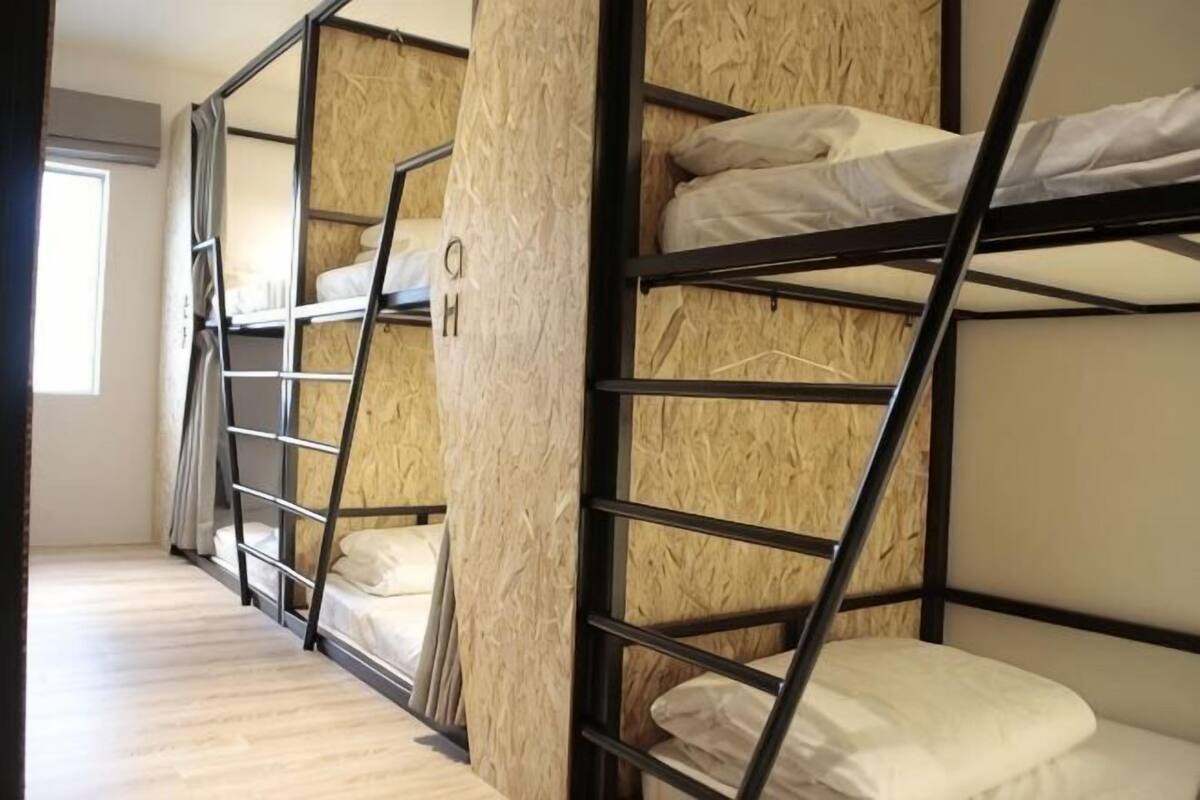 Des lits superposés avec des panneaux en bois et une structure en métal, une fenêtre et un plancher en bois.