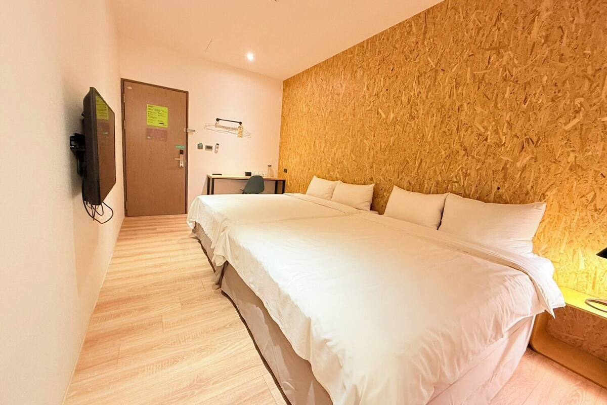 Une chambre d’hôtel dotée d’un grand lit, d’un bureau, d’une télévision et d’un mur décoratif en bois.