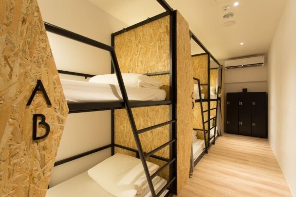 A bunk bed room with a wooden wall and a wardrobe in the background.