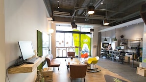 A modern office space with a wooden desk, computer, and seating area. - Let’s Hostel (Kaohsiung)