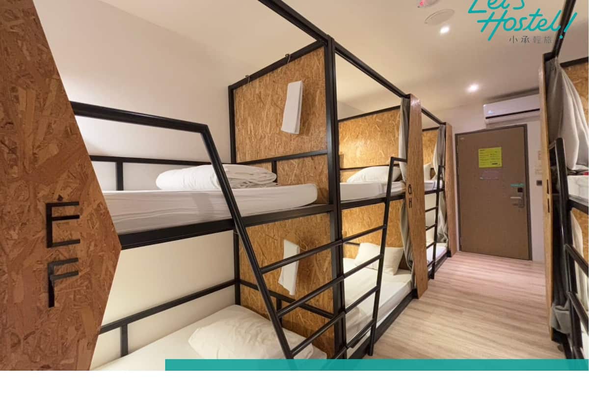 Une chambre avec des lits superposés, un mur en bois et une porte avec une pancarte.