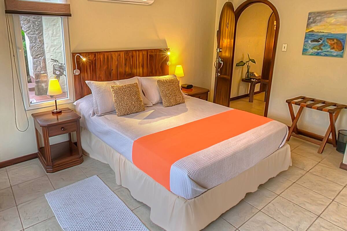 Une chambre à coucher bien rangée, avec un lit, des tables de chevet, une lampe et un miroir.