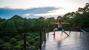 Une personne effectuant une posture de yoga sur une terrasse carrelée, avec une forêt en arrière-plan.