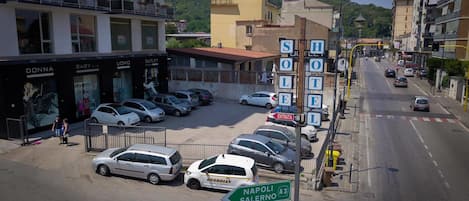 A street view with a row of parked cars, a sign for 'NAPOLI SALERNO A3', and a building with 'OUTLET' signage.