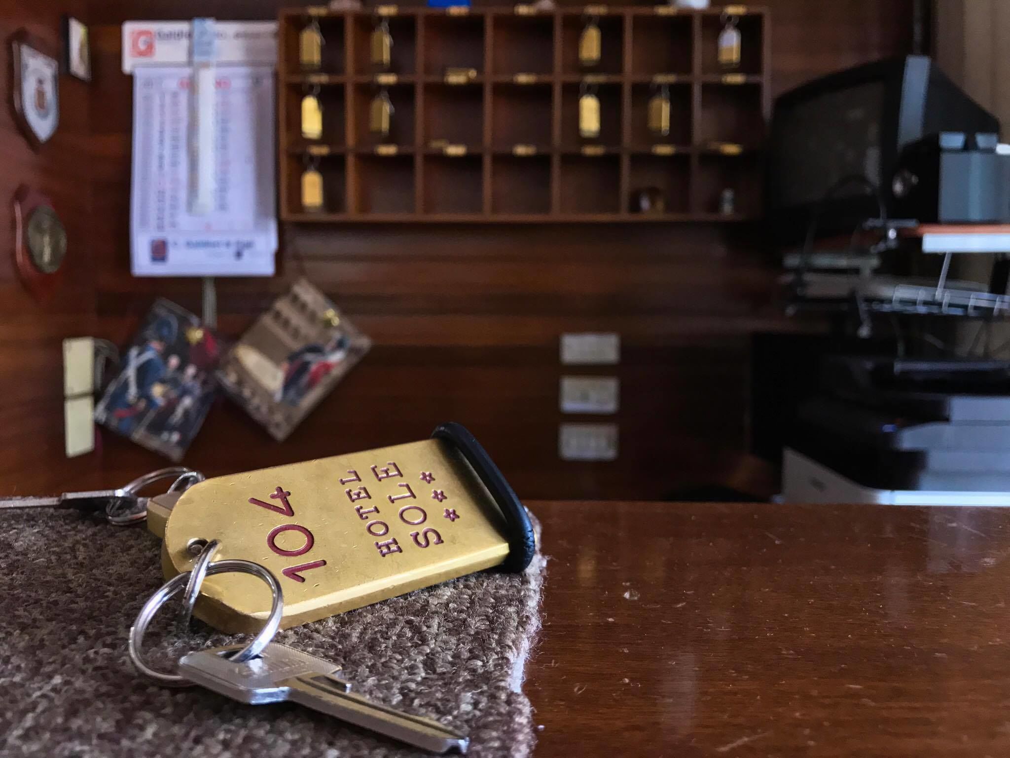 A hotel reception desk with a keychain, keys, and a wooden display cabinet in the background.