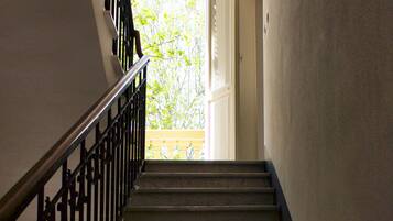 A staircase with a metal railing leading to a bright room with a view of trees.