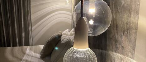 Une chambre à coucher moderne avec un lit, un luminaire suspendu et une lampe fixée au mur.