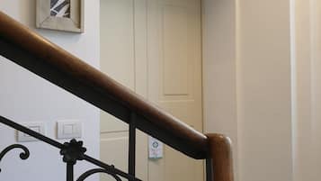 Een trap met een houten leuning en zwarte metalen spijbels. Boven de trap bevindt zich een witte deur.